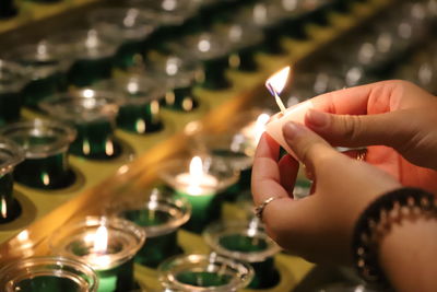 Cropped hands of woman holding tea light candle in cathedral