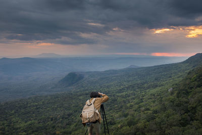 Woman on landscape against cloudy sky