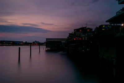 Illuminated buildings in city against sky at sunset
