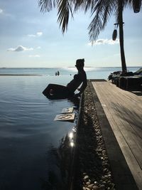 Man on pier over sea against sky