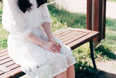 Midsection of woman sitting on bench in park