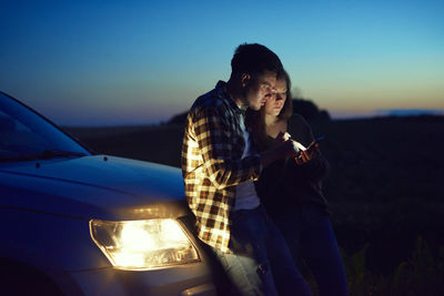 Couple using mobile phone at dusk