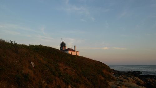 View of lighthouse by sea against sky during sunset
