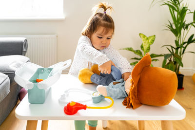 Cute baby girl sitting on table at home