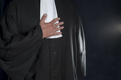 Midsection of judge standing against black background