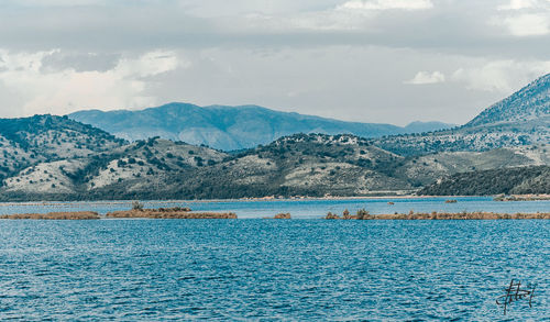 Scenic view of sea by mountains against sky