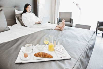 Businesswoman having breakfast in bed in luxury business hotel