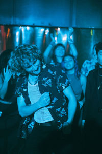 Cheerful multiracial male and female friends enjoying while dancing in club