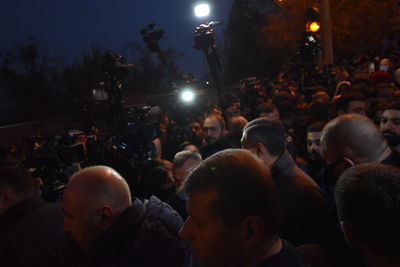 People looking at illuminated street in city at night