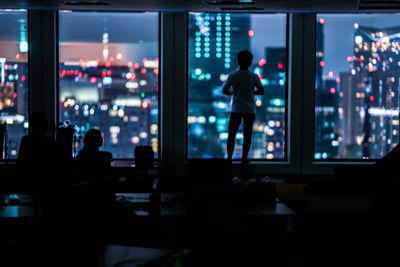 Rear view of silhouette people standing in city at night