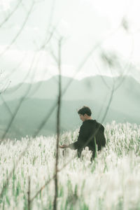 Side view of young man standing on field