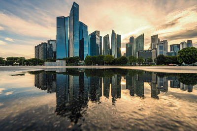 Reflection of buildings in lake against sky in city
