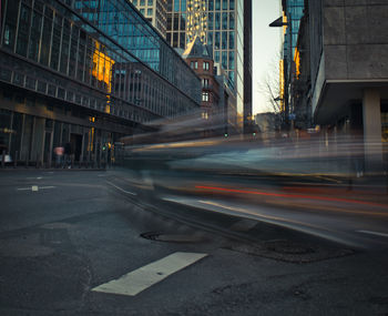 Light trails on road by buildings in city