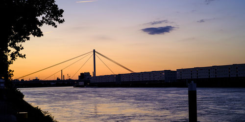 Silhouette bridge over river against sky during sunset