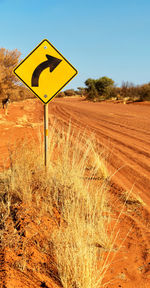 Road sign on field against clear sky