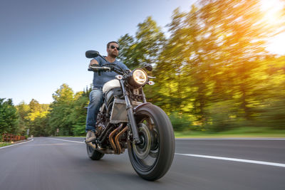 Man riding motorcycle on road against sky