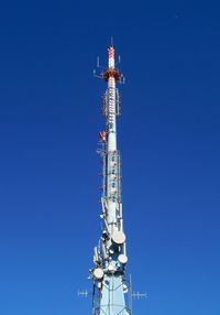 Low angle view of communications tower against blue sky