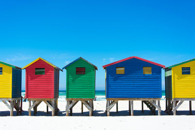 Row of houses on beach against clear blue sky