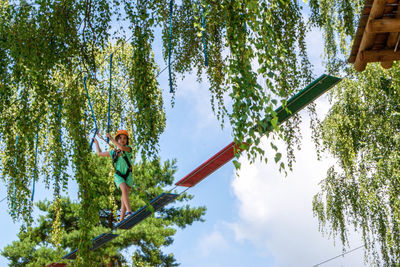 Adventure climbing high wire park - people on course in mountain helmet and safety equipment