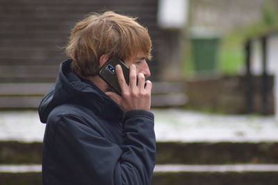 Side view of mid adult man talking on mobile phone while standing outdoors