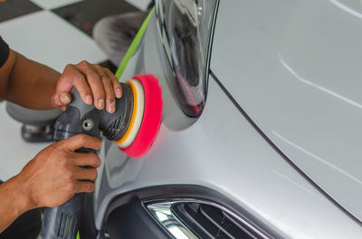 Midsection of mechanic polishing car in auto repair shop