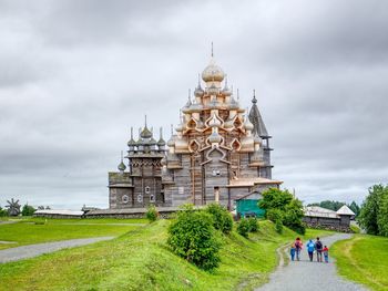 People at temple against cloudy sky