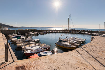 Boats moored at harbor against clear sky on sunny day