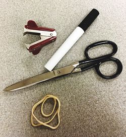 High angle view of pen with stapler and rubber band by scissors on table