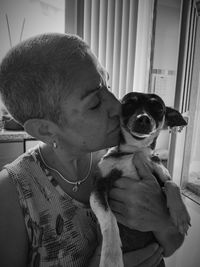 Woman kissing dog at home