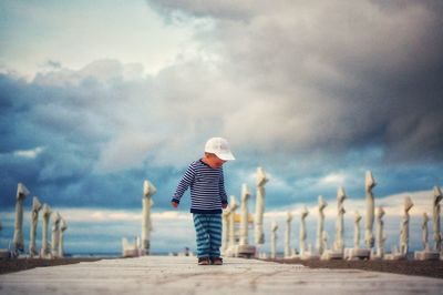 Rear view of boy on beach against sky