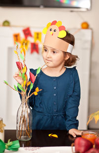 Cute girl wearing headband sanding by vase