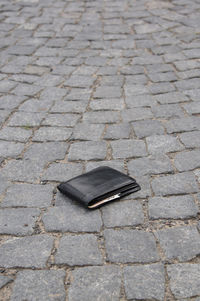 High angle view of wallet on cobble street