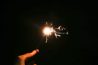 Person hand holding sparkler at night