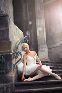 Full length of woman sitting against wall