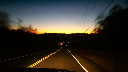 Car moving on road against sky during sunset