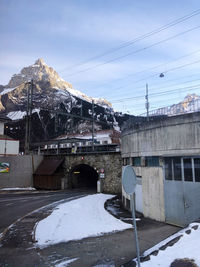 Snow covered houses by mountain against sky