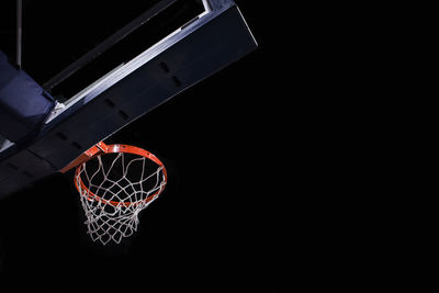 Low angle view of basketball hoop against black background