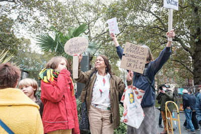 People standing on street against trees in city