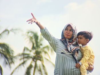 Girl standing with soon against sky