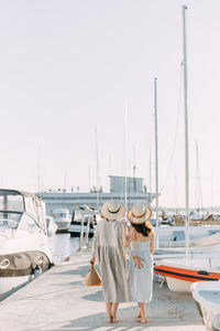 Two women friends walk along the pier along the boats and yachts