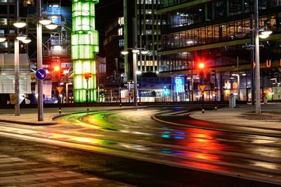 Light trails on city street by buildings at night