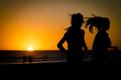 Silhouette people at beach during sunset