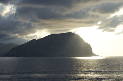 Scenic view of sea and mountains against dramatic sky