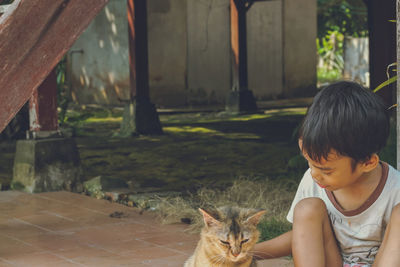 Rear view of a boy looking at cat