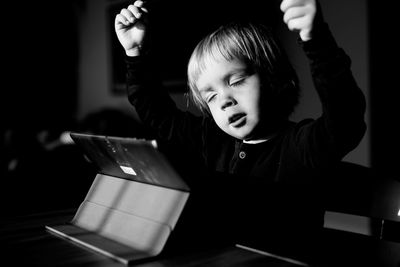 Boy with eyes closed by digital tablet on table at home