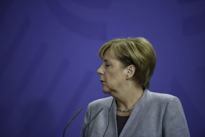 Portrait of woman looking away against blue wall