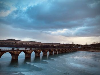 Arch bridge over river against sky