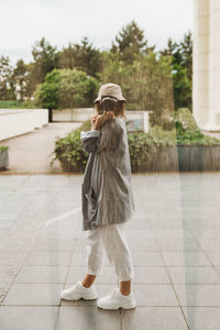 Full length of woman with umbrella standing against trees