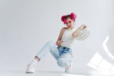 Full length of young woman with arms raised against white background