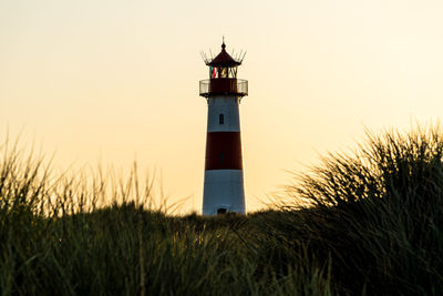 Lighthouse by sea against clear sky